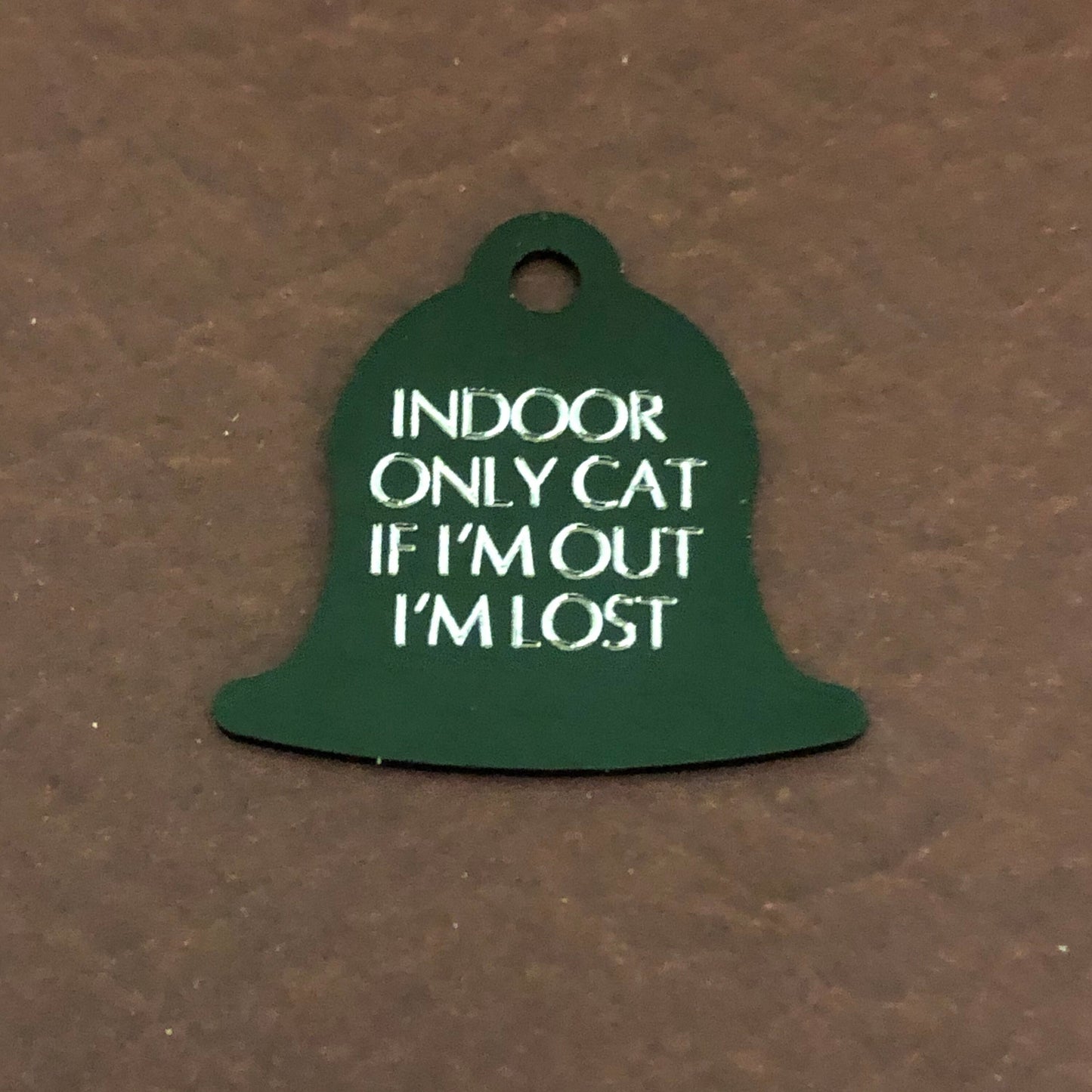 Small green bell tag that says: Indoor only cat If I'm out I'm lost. All engraved in capital letters.