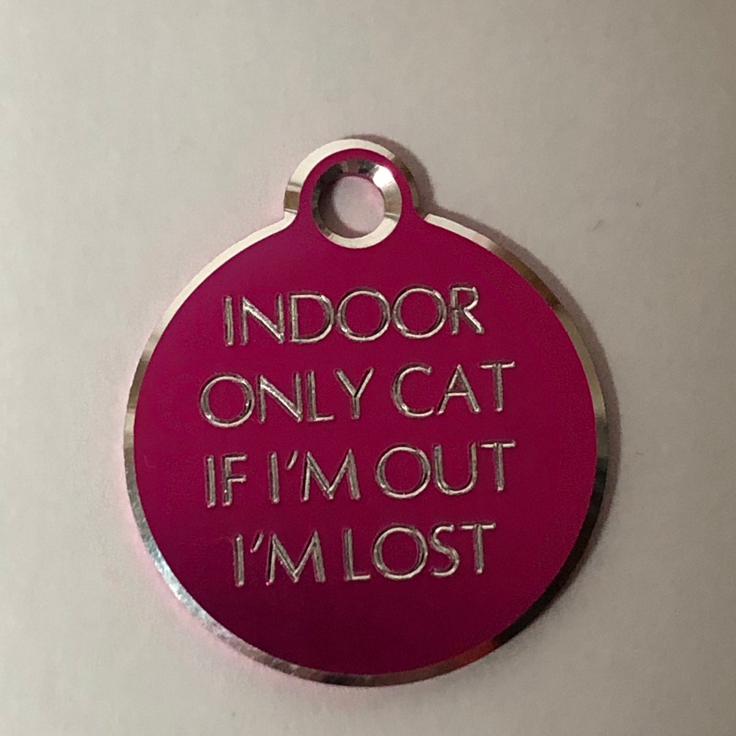 Small Hi-LITE pink circle tag that says: Indoor only cat If I'm out I'm lost. All engraved in capital letters.
