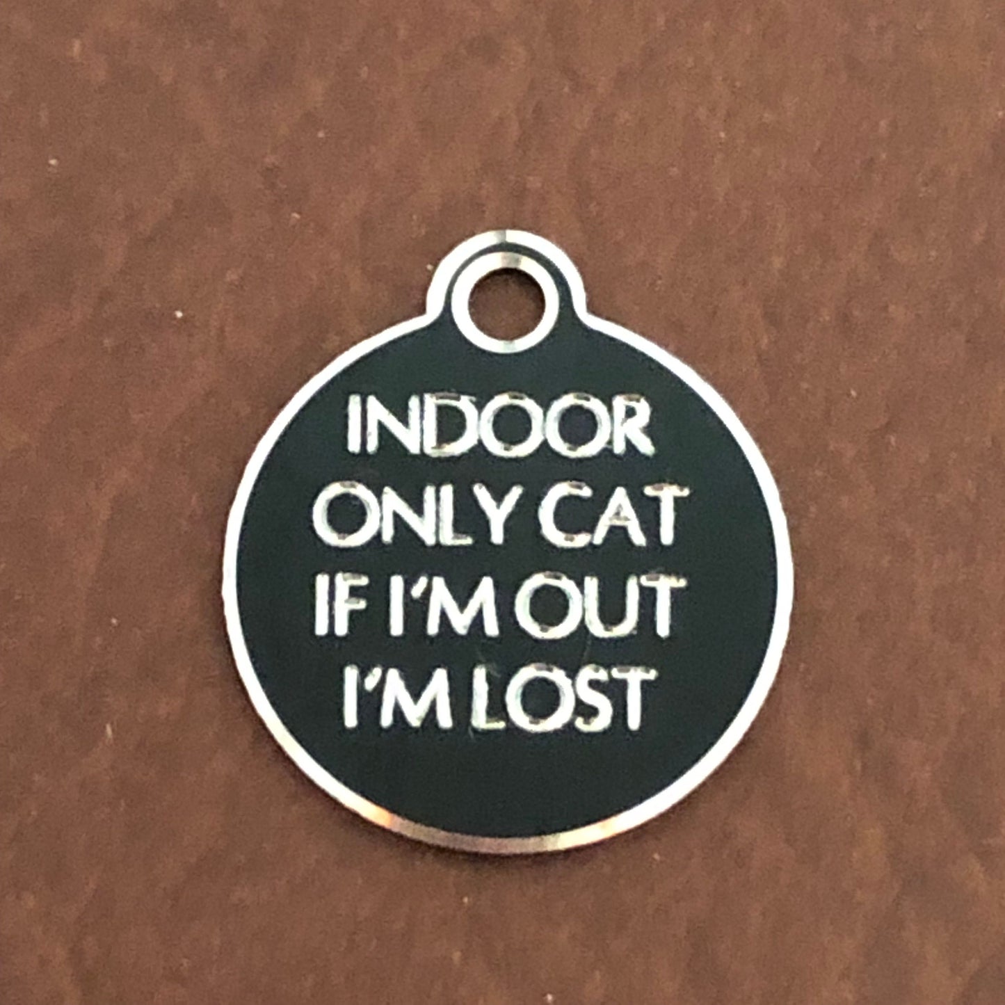 Small Hi-LITE black circle tag that says: Indoor only cat If I'm out I'm lost. All engraved in capital letters.