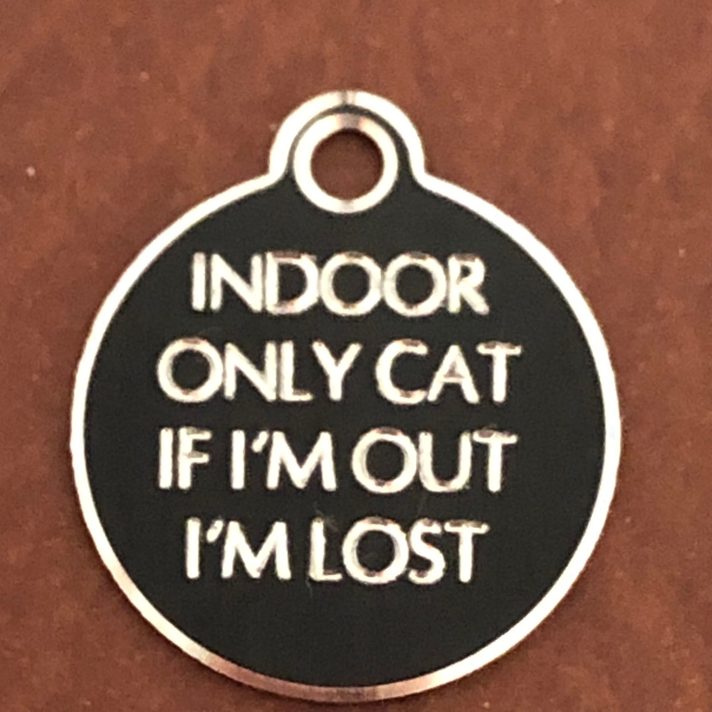 Small Hi-LITE black circle tag that says: Indoor only cat If I'm out I'm lost. All engraved in capital letters.