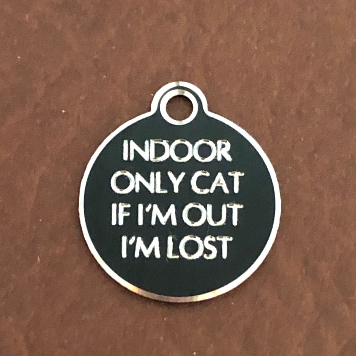 Small Hi-LITE black circle tag that says: Indoor only cat If I'm out I'm lost. All engraved in capital letters.